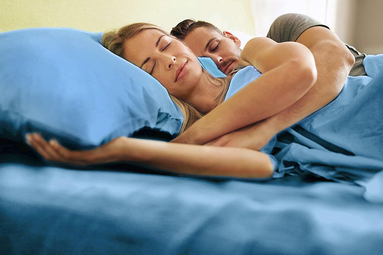tes Man and woman laying in bed with denim blue sheets