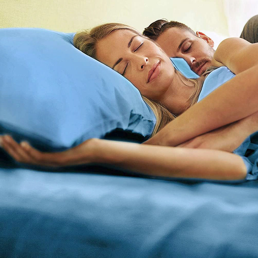 Man and woman laying in bed with denim blue sheets