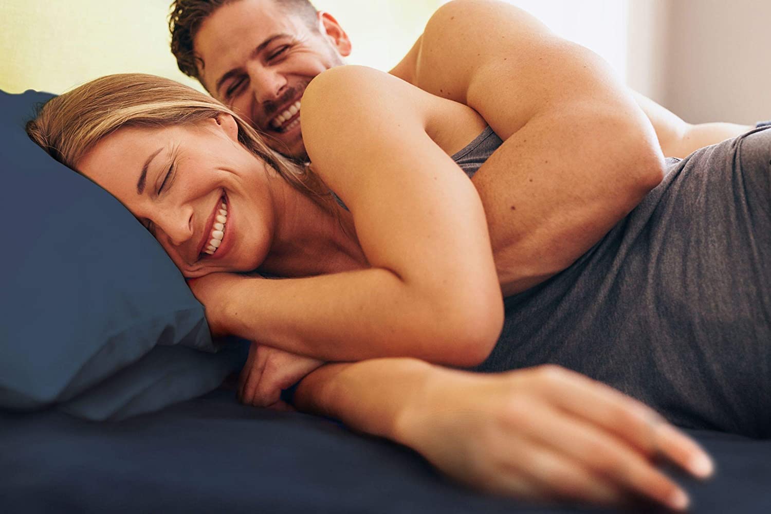 Man and woman laying in bed with navy blue sheets